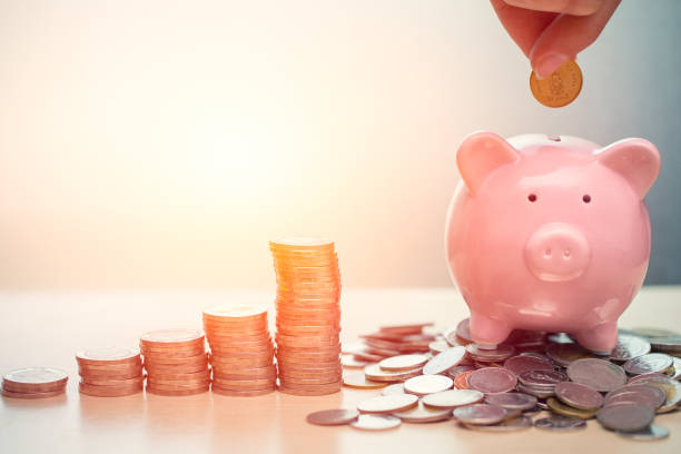 Stack of coins and piggy bank with coin being inserted